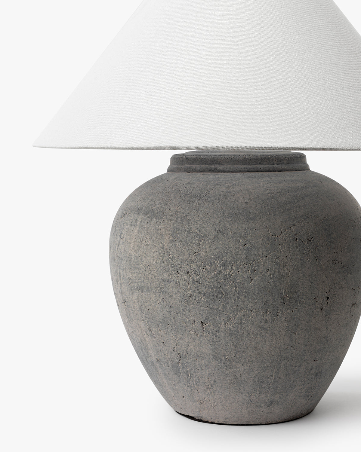 A close-up of the Montague Table Lamp with a textured gray ceramic base and a white cone-shaped lampshade, shown against a plain white background, by McGee & Co.