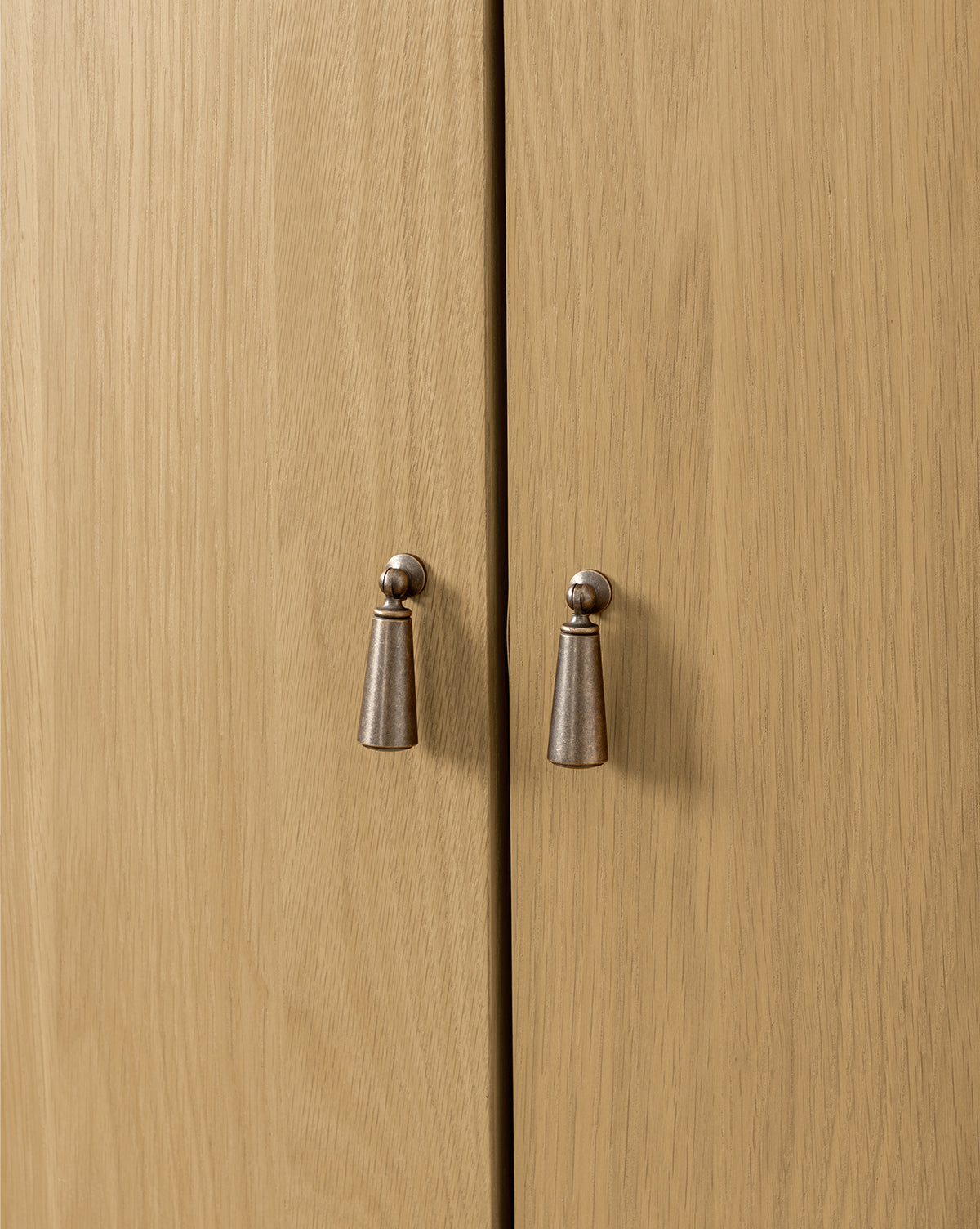 Close-up of two metal handles on light wood doors with a natural grain, perfect for the Moorland Cabinet or living room storage, by McGee & Co.
