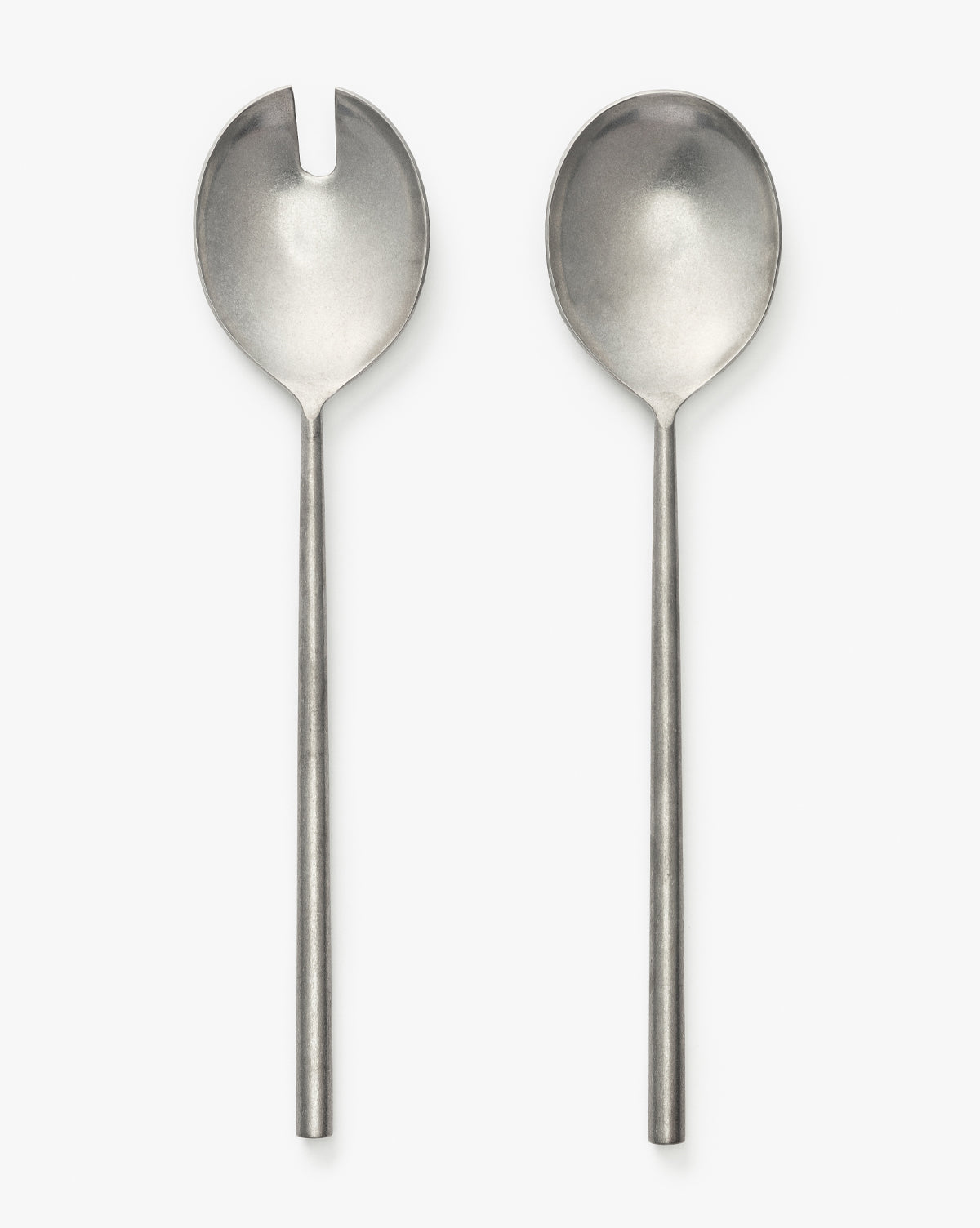 The Mortensen Salad Servers (Set of 2) feature two stainless steel utensils with long handles; the spoon on the left has a notch near its rim, while the right one is unnotched. Both are shown side by side on a white background by McGee & Co.