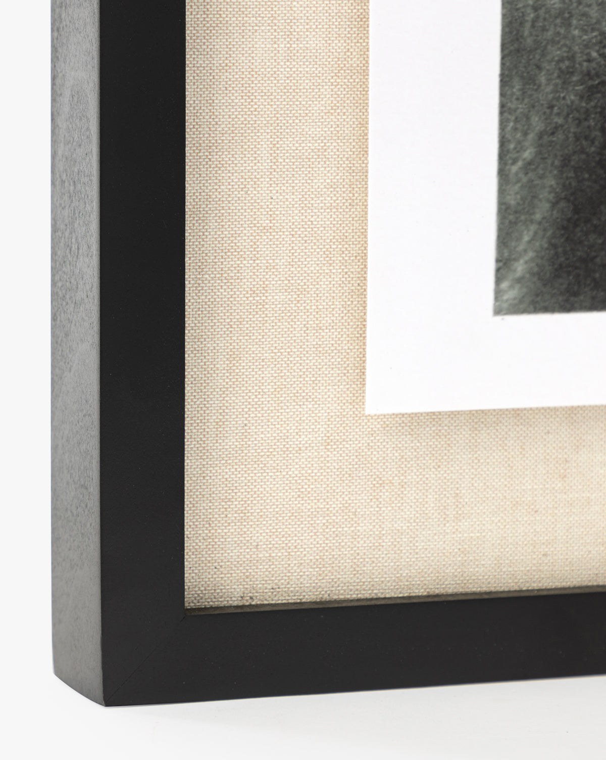 Close-up of the corner of a black frame with white mat, textured beige background, and partially visible giclee print—Muted Florida Pines by Carol Haymon.