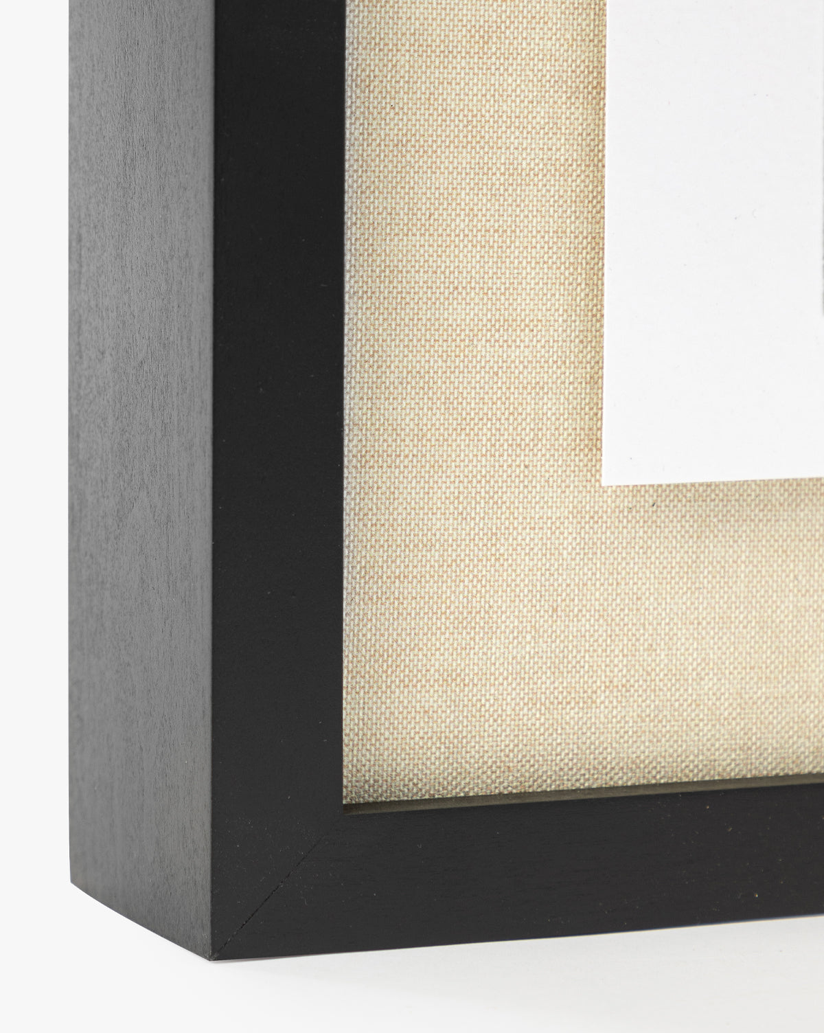 Close-up of the corner of an American Maple frame with a beige textured mat and white border, showcasing Muted Path Green by Carol Haymon.