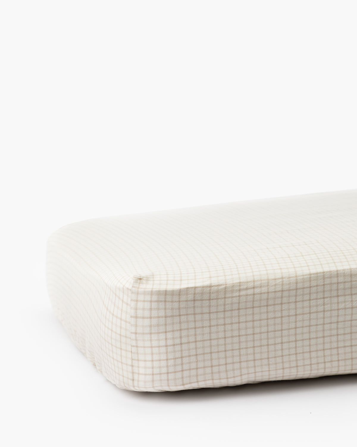 A close-up of the Nell Crib Sheet, a fitted white cotton childrens bedding with a light beige grid pattern, displayed against a plain white background.