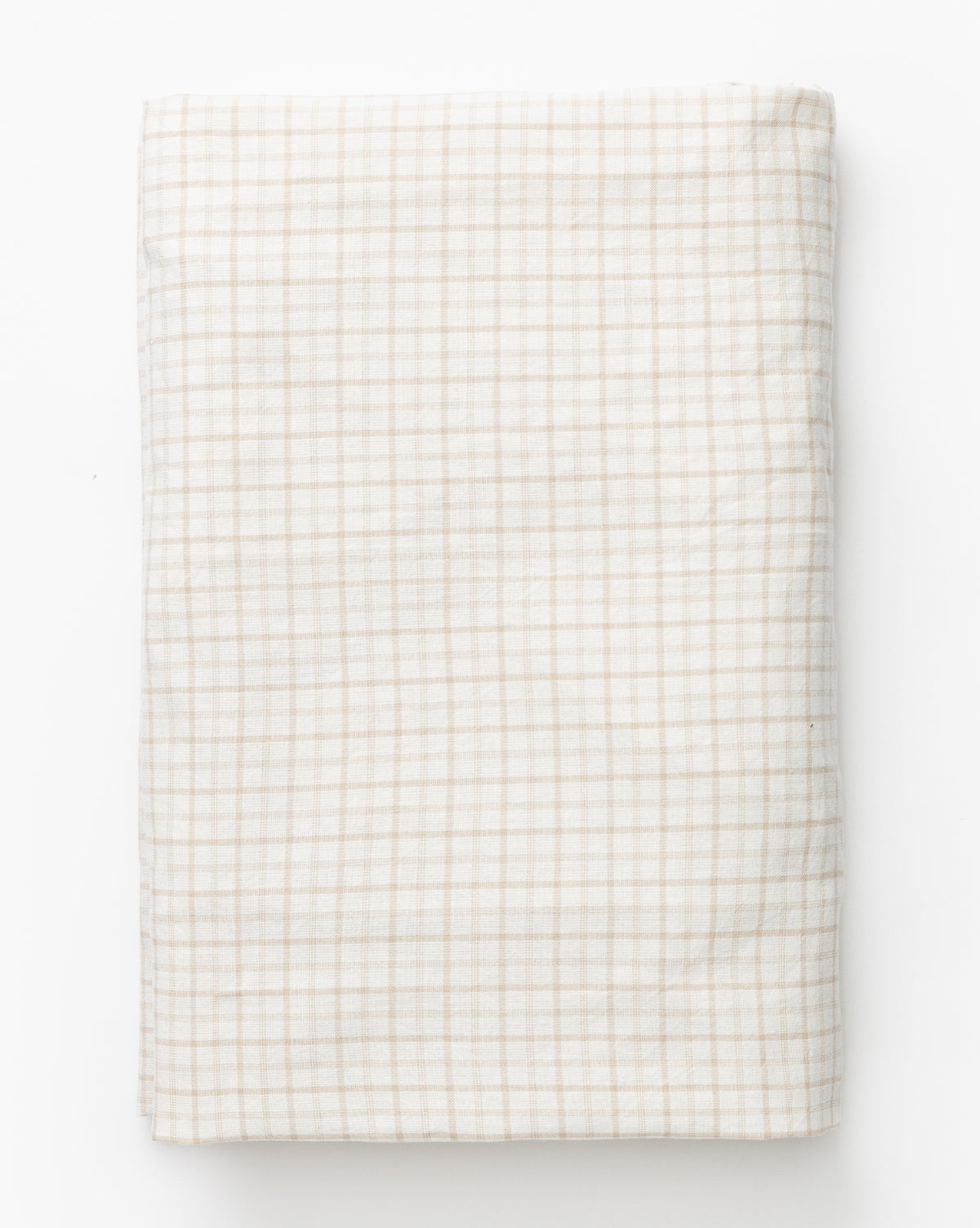 The Nell Crib Sheet is a neatly folded beige and white cotton bedding fabric featuring a simple checkered grid pattern, displayed on a white background.