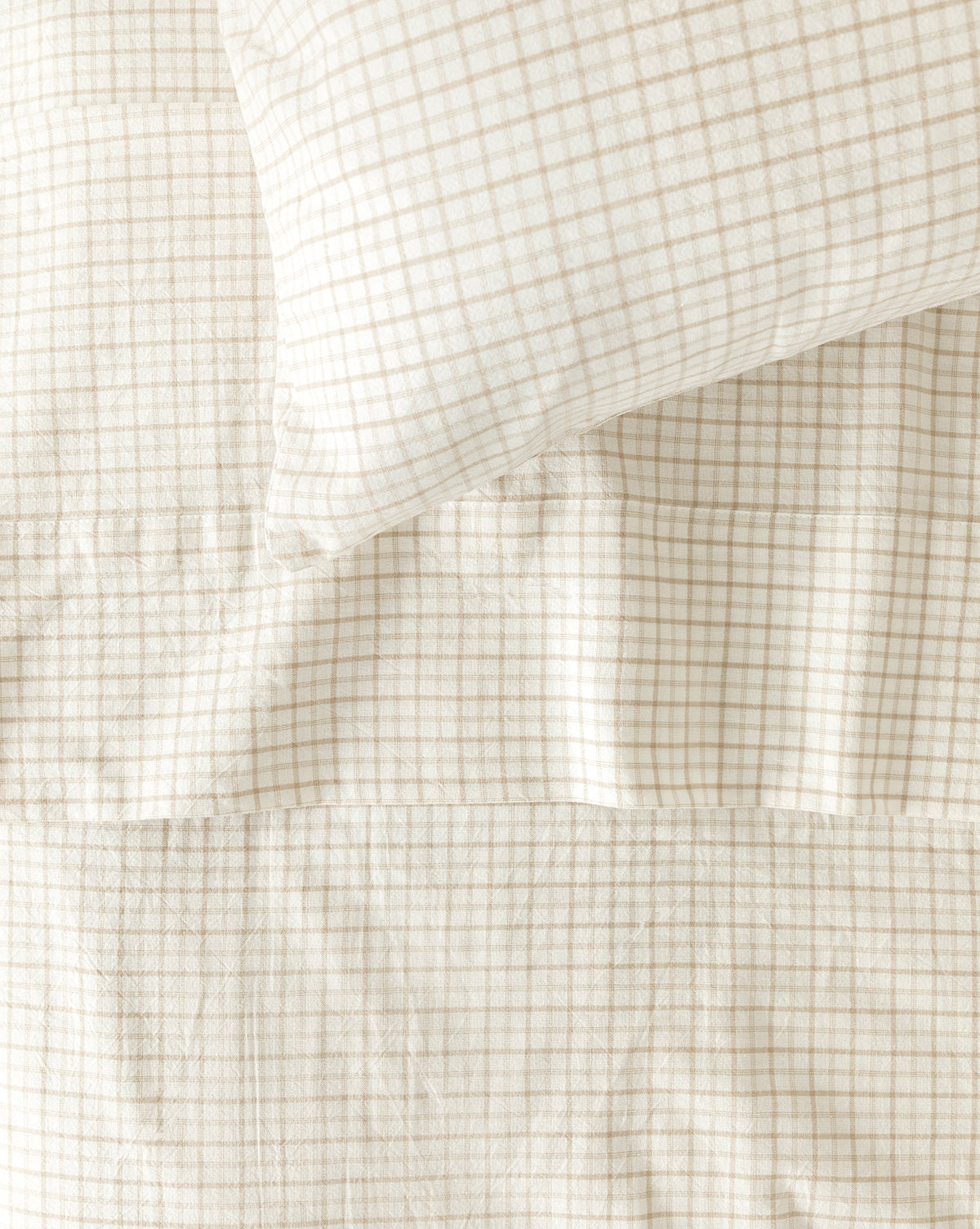 The Nell Twin Kids Sheet Set features a cream-colored pillow and blanket with a subtle beige grid pattern and soft cotton sheets—ideal for children’s bedding or creating a cozy, neatly made bed.