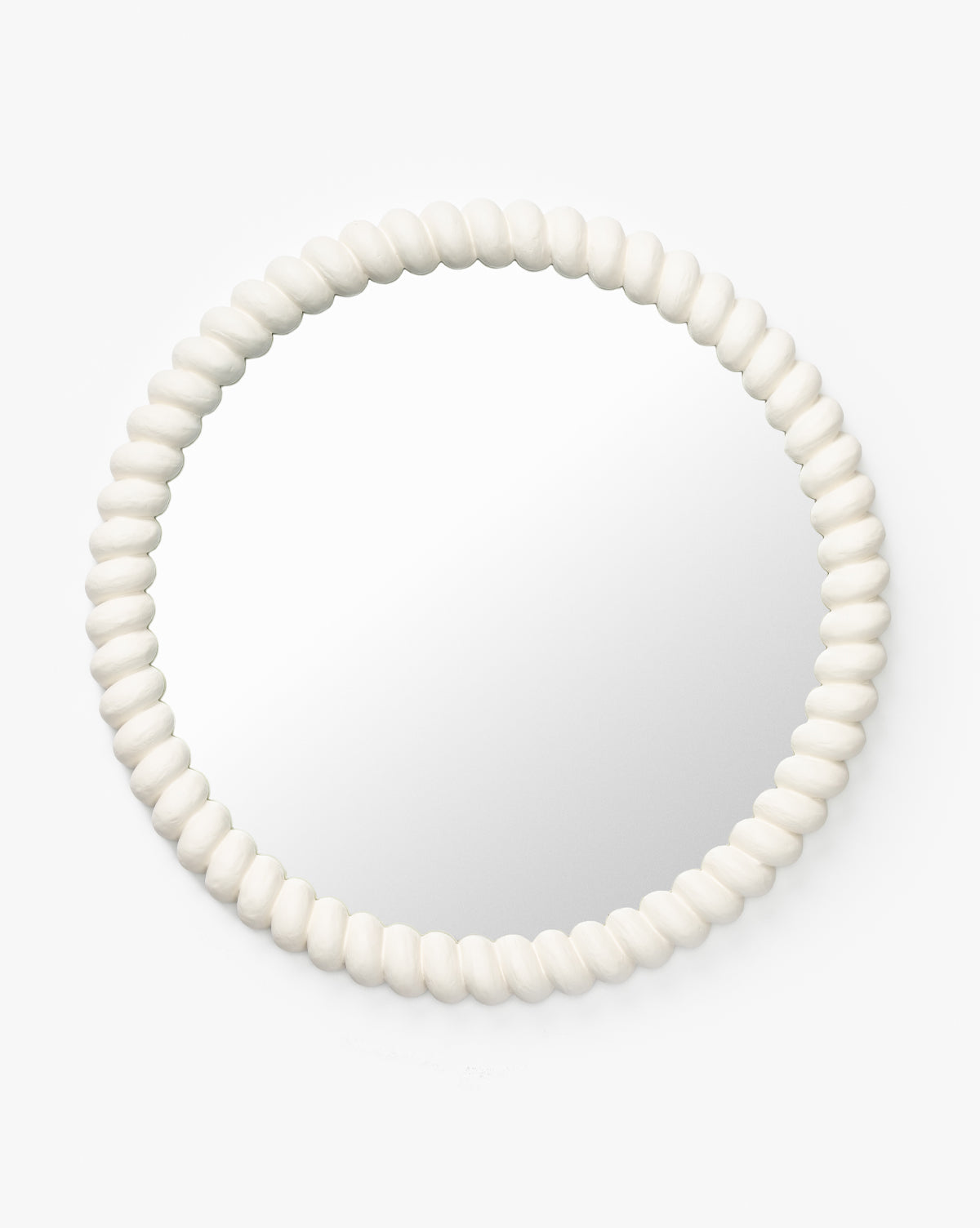 The Norina Mirror is round with a white, textured, beaded frame resembling smooth oval beads—an ideal accent for coastal decor, by McGee & Co.