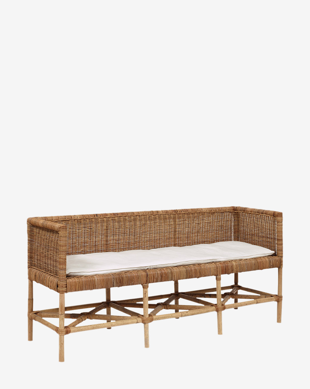 The Odelia Bench is a rectangular rattan bench with armrests and a backrest, featuring a light beige seat cushion and a performance fabric pillow, shown against a plain white background.