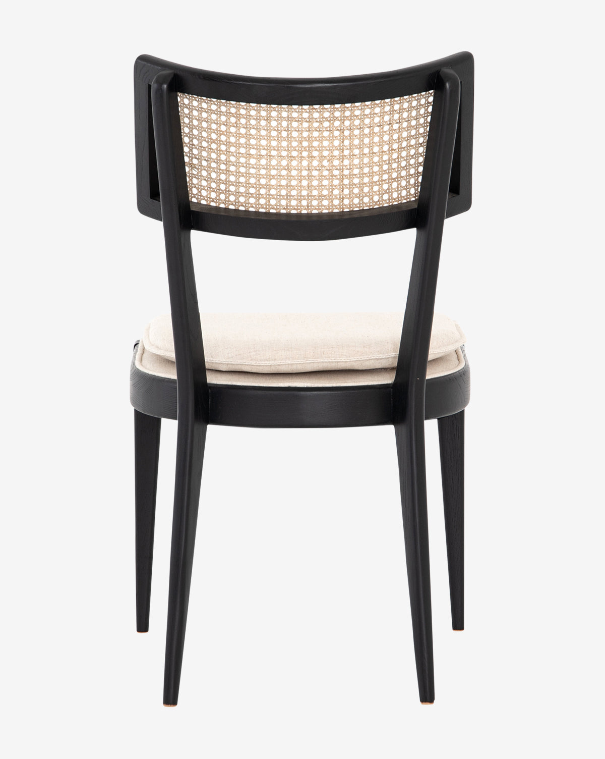 The Odelle Dining Chair is a black wooden chair with a woven cane backrest and light beige cushioned seat, viewed from the back. It features straight legs and a minimalist, modern style by McGee & Co.