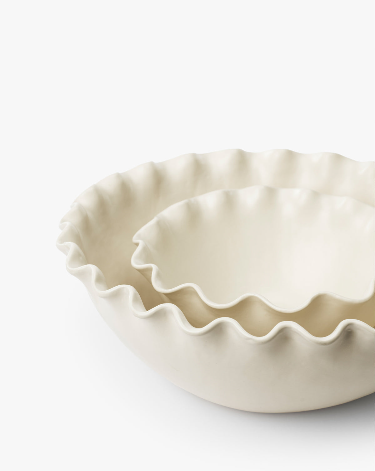 The Olindo Serving Bowls (Set of 2) feature cream-colored bowls with ruffled, wavy edges, perfectly nested together. The smaller vintage-inspired bowl fits neatly inside the larger one against a white background, by McGee & Co.