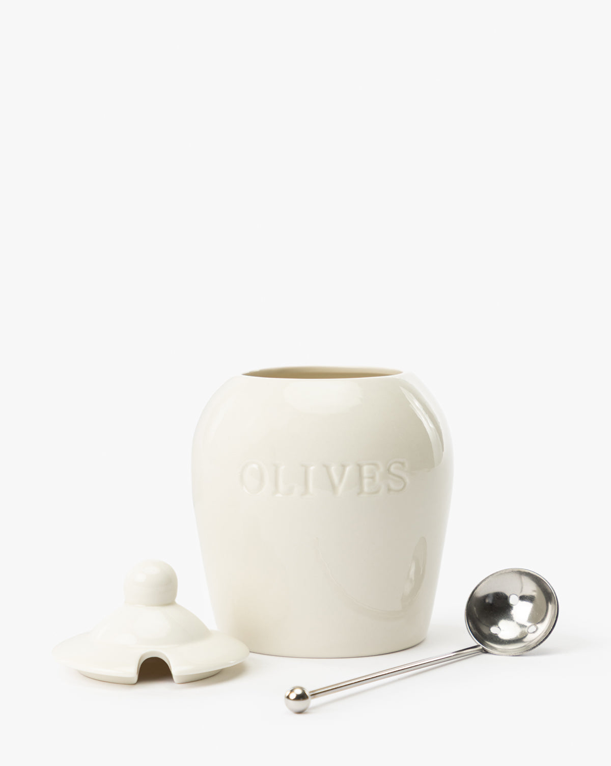 The Olive Stoneware Jar, labeled OLIVES, comes with a matching lid and airtight seal. A silver slotted spoon rests beside it, all displayed against a plain white background, by McGee & Co.
