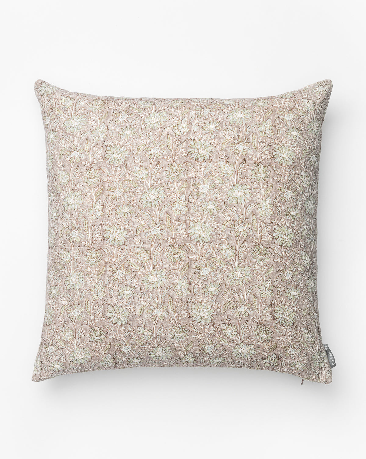 The Opal Pillow Cover showcases a subtle light pink and beige floral pattern on fabric, features a small fabric tag at the bottom right edge, and is photographed against a plain white background by McGee & Co.