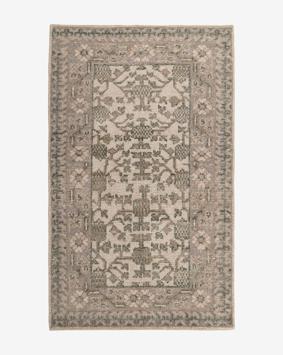 The Orsino Hand-Knotted Rug is a rectangular, antique-style piece featuring a muted, vintage-inspired pattern with geometric and floral motifs in beige, gray, and green tones. A decorative border frames its intricate central design by McGee & Co.