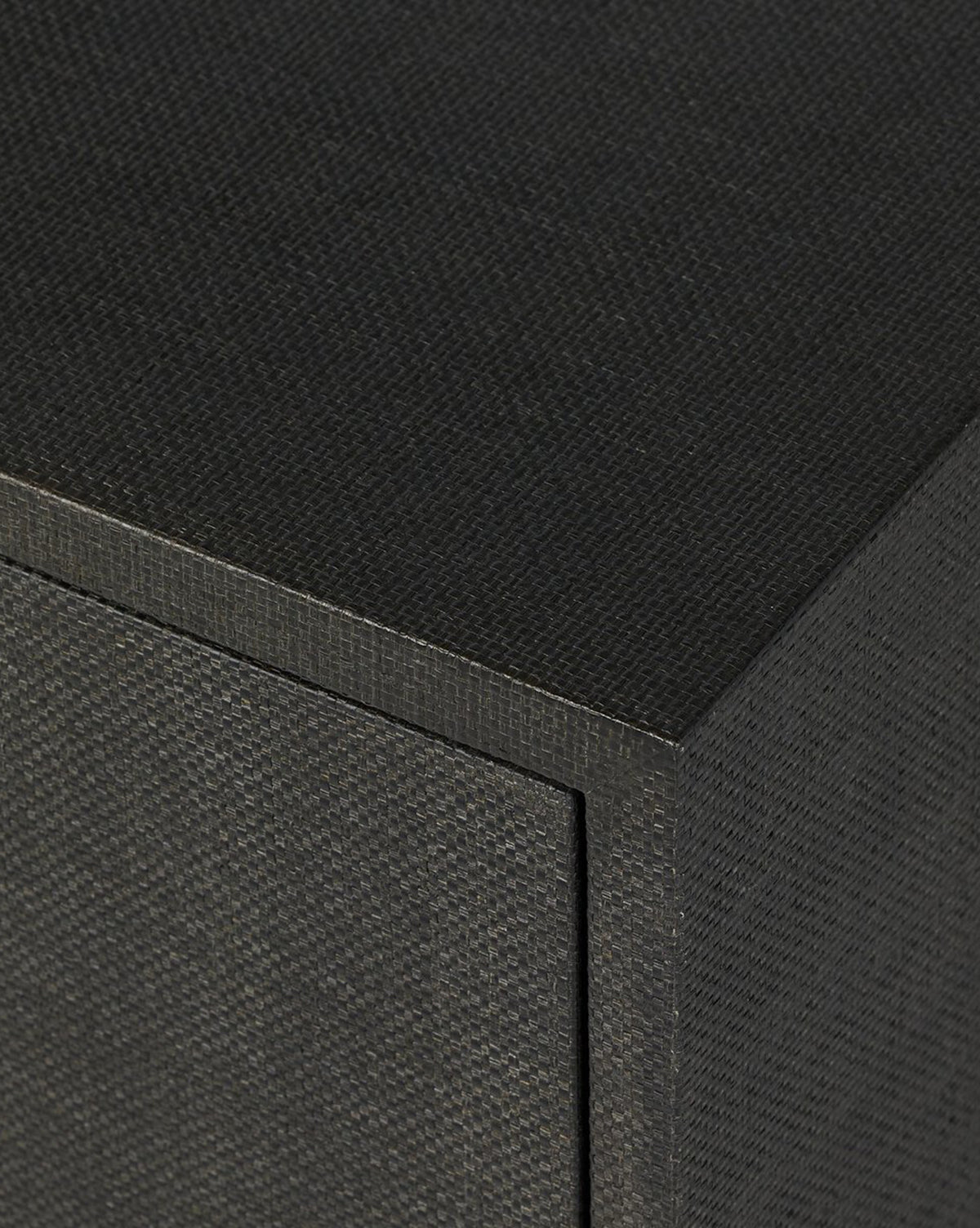 Close-up of the corner of the Osborne Cabinet, highlighting its textured, dark black raffia finish and detailed grain, by McGee & Co.
