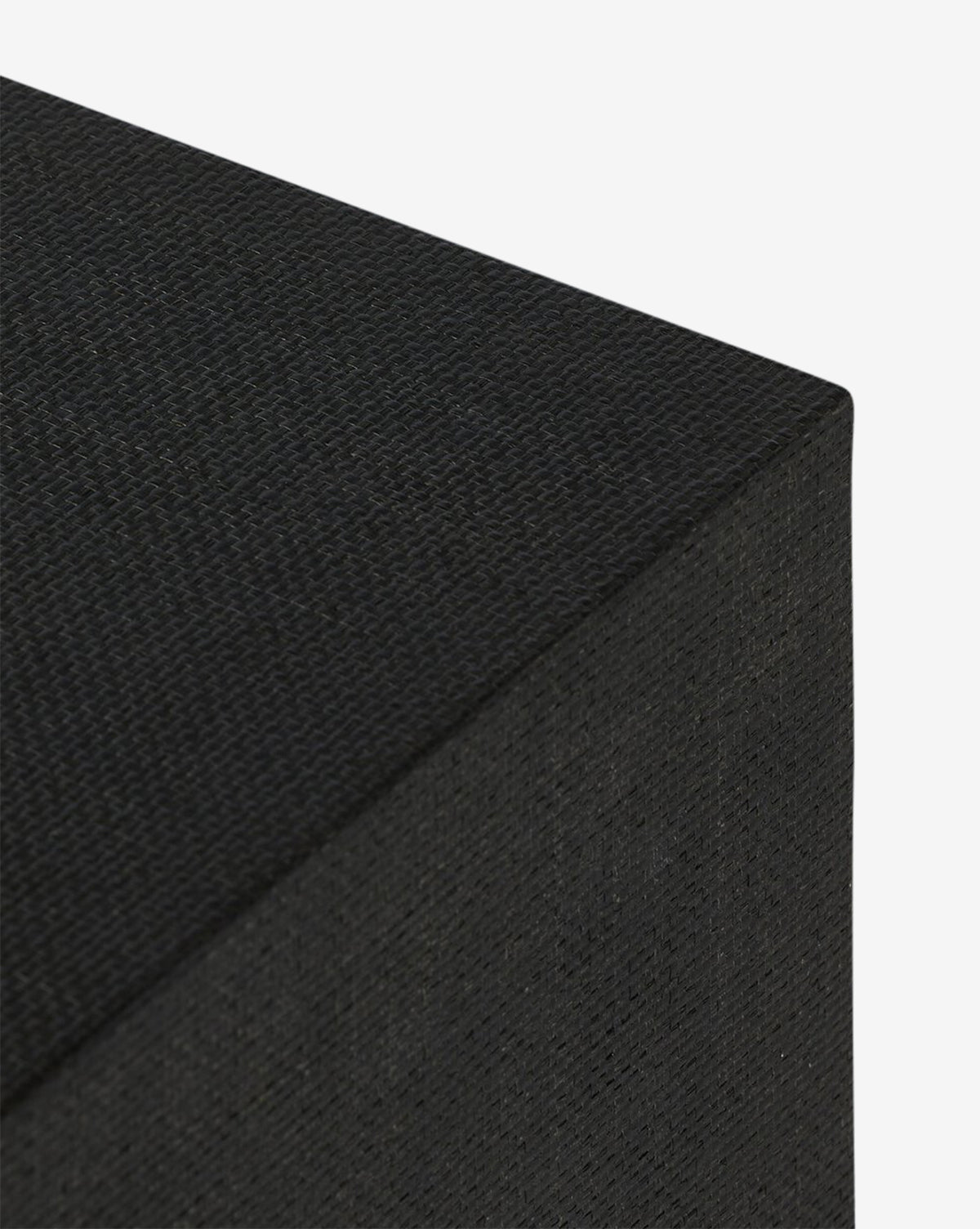Close-up of the Osborne Cabinets top front corner, showcasing its black raffia, fabric-like textured surface and sharp edges against a white background, by McGee & Co.