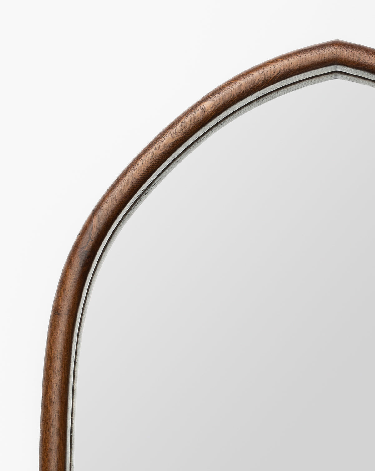 A close-up of the Oslo Mirror showcases its oak frame with a smooth brown finish and gentle curves, set against a plain white background, by McGee & Co.