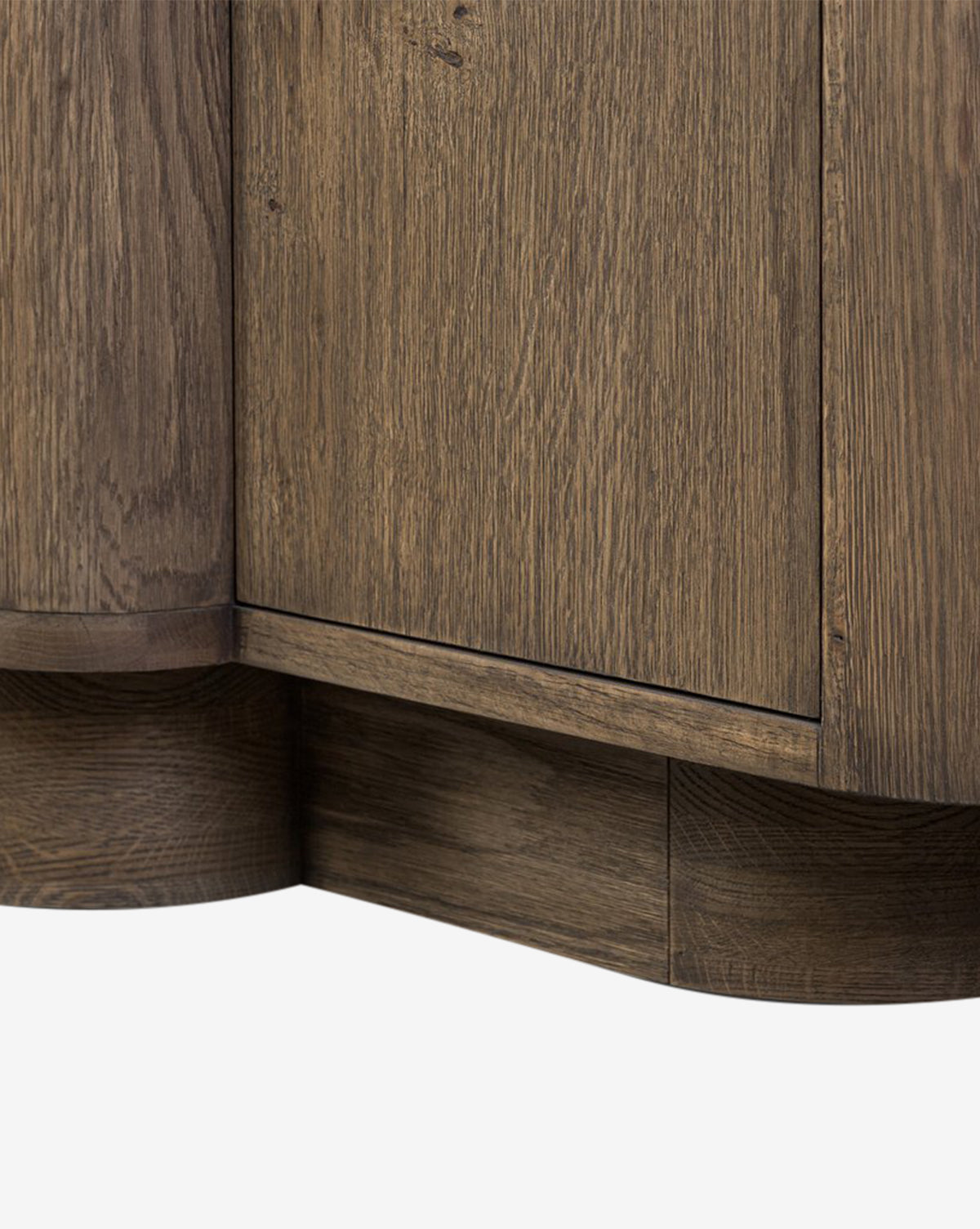 Close-up of the lower corner of the Oswin Sideboard, displaying its weathered oak finish, visible wood grain, and rounded base details against a white background, by McGee & Co.