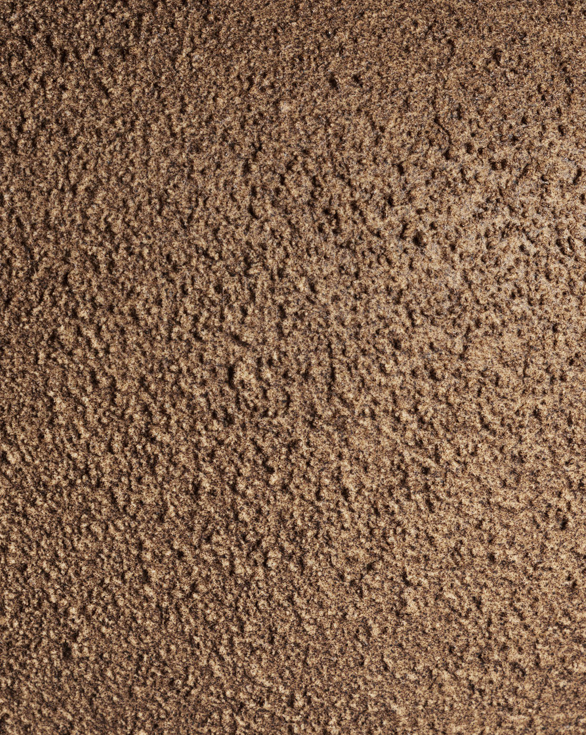 Close-up of a rough, brown, crumbly surface with uneven, grainy texture, similar to the naturally textured ceramic base of the Parma Table Lamp by McGee & Co.