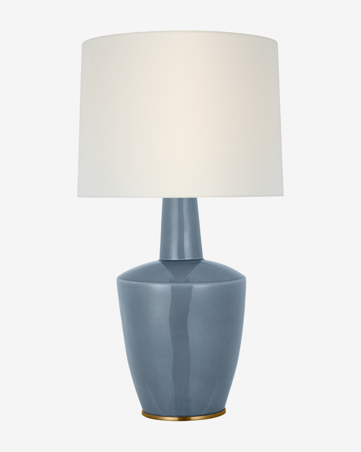 The Paros Table Lamp has a glossy blue ceramic base with a narrow neck, a round white fabric lampshade, and sits on a small gold-colored base by McGee & Co.