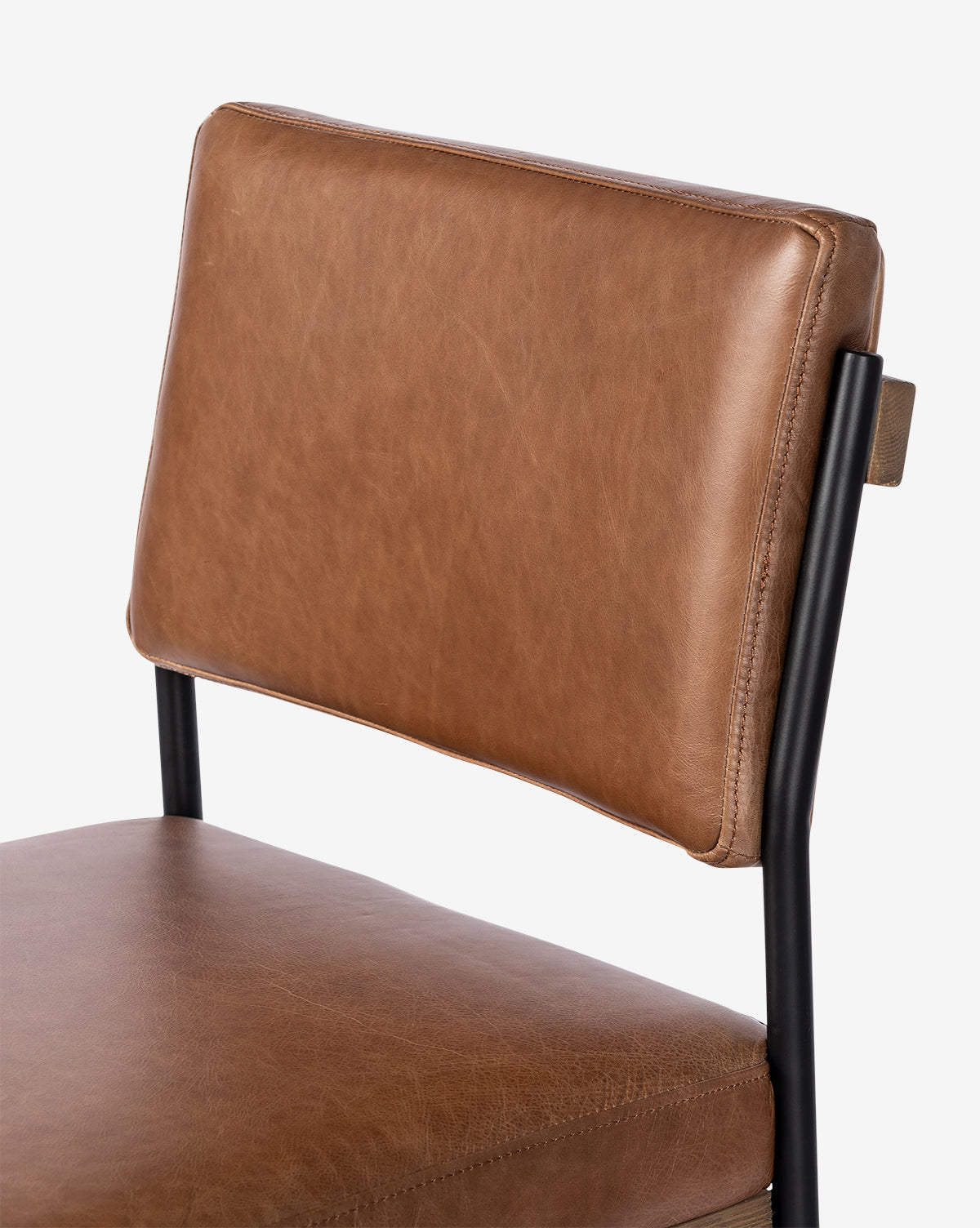 A close-up view of the Pascal Stool highlights its brown leather seat and backrest paired with a black iron frame, set against a plain white background, by McGee & Co.