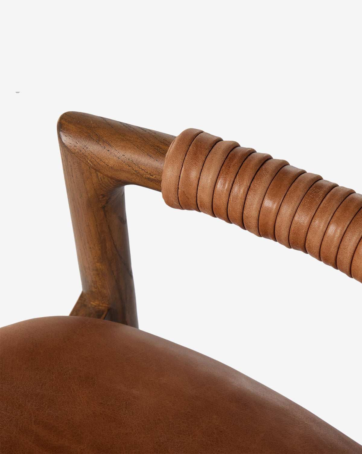 Certainly! Here’s a blended description incorporating your requested string: Close-up of the Four Hands Patrin Stool’s ash wood frame, with a smooth brown leather-wrapped armrest and performance upholstered seat, set against a plain white background—McGee & Co.