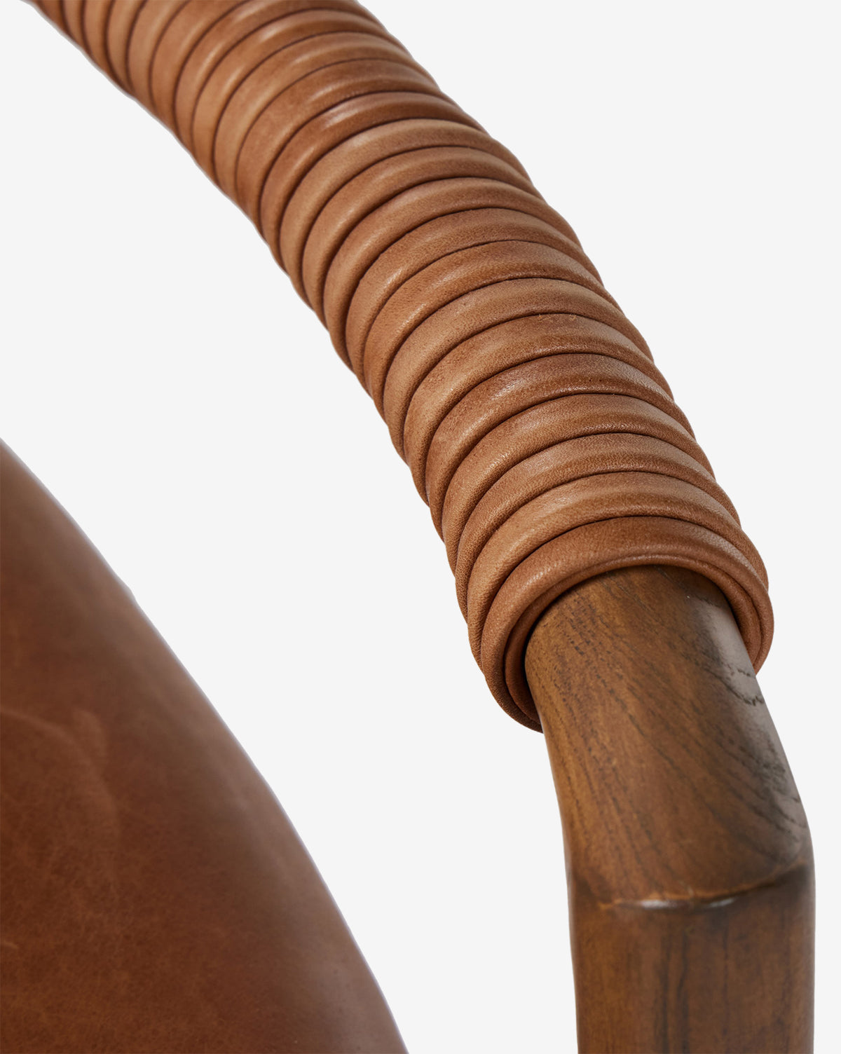 Close-up of a Four Hands Patrin Stool armrest in ash wood, wrapped with light brown leather loops, beside a matching performance-upholstered seat. McGee & Co.