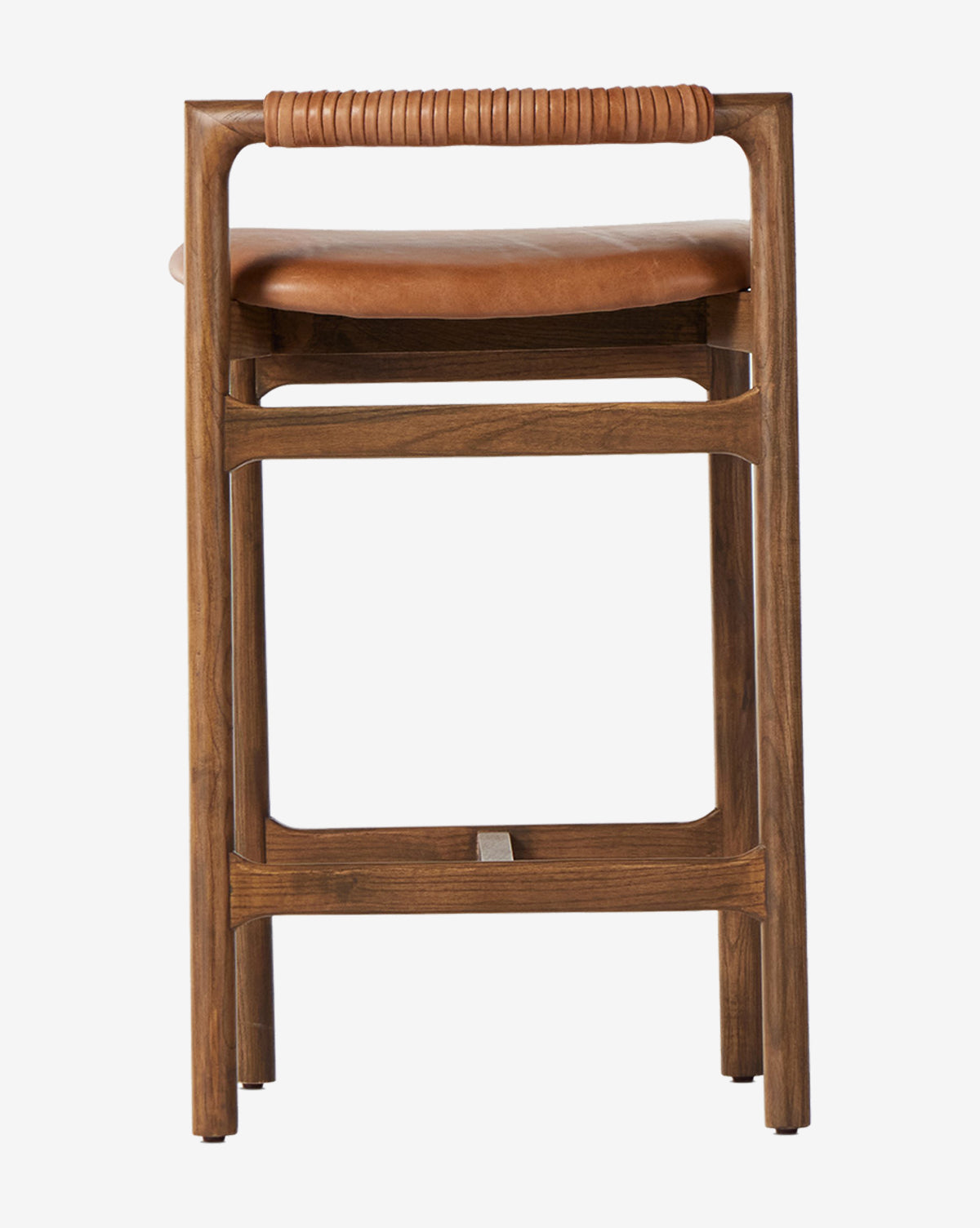 The Four Hands Patrin Stool has an ash wood frame and a tan leather seat with wrapped leather detail on the top rail, shown from the front against a white background. McGee & Co.