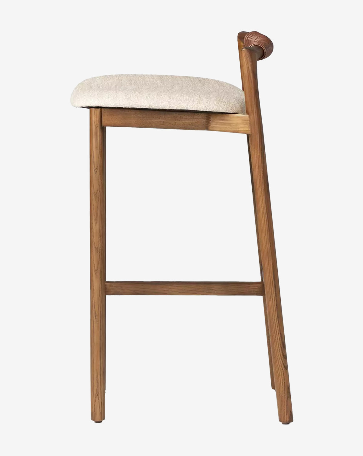 The Four Hands Patrin Stool features an ash wood frame, light beige performance upholstery, and a low curved backrest, shown in profile against a plain white background. McGee & Co.