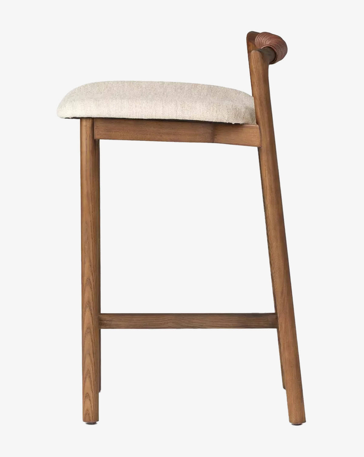 The Patrin Stool by Four Hands has an ash wood frame, angled backrest, beige performance-upholstered seat, and footrest, shown in side profile against a plain white background. McGee & Co.