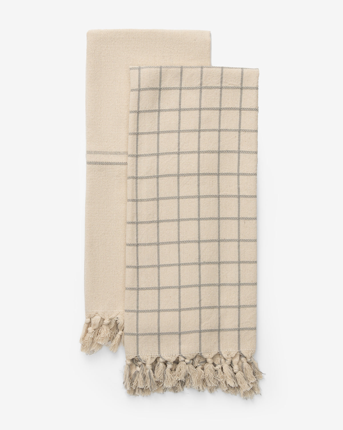 The Peabody Cotton Tea Towel Set includes two beige towels—one striped, one with a gray grid—each finished with tasseled fringes, adding charming style to your kitchen decor, by McGee & Co.