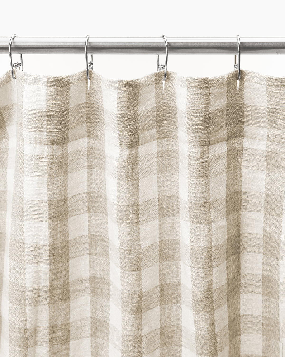 The Pennie Shower Curtain, with its beige and white gingham checkered design and natural textured fabric, hangs from a silver rod with metal hooks, adding charm to any bathroom.