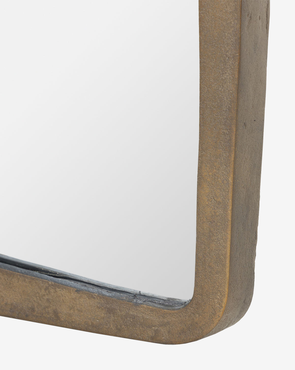 Close-up of the Penrod Floor Mirror’s corner, featuring a thick, rustic bronze-hued cast aluminum frame. The partially visible mirror reflects a white background—ideal as sculptural decor for any home, by McGee & Co.