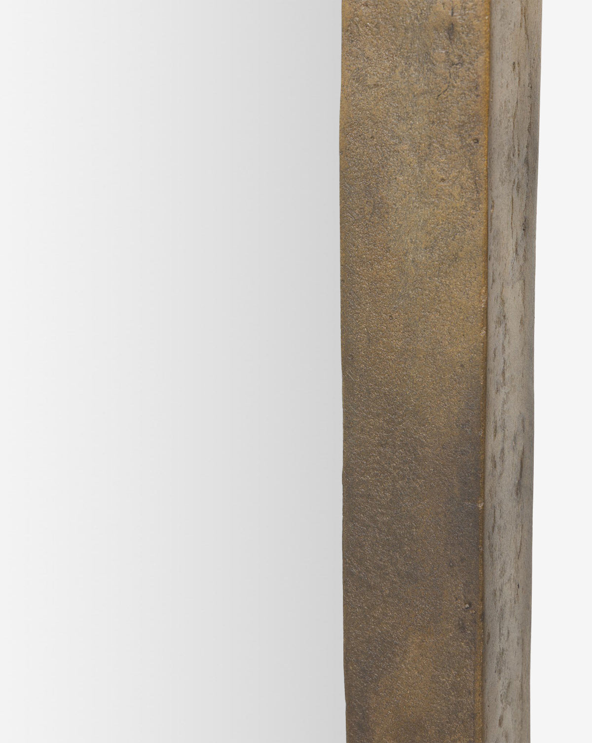 Close-up of the Penrod Floor Mirror, showcasing its thick, textured weathered gold or bronze-colored cast aluminum frame on the right and reflective surface on the left, by McGee & Co.