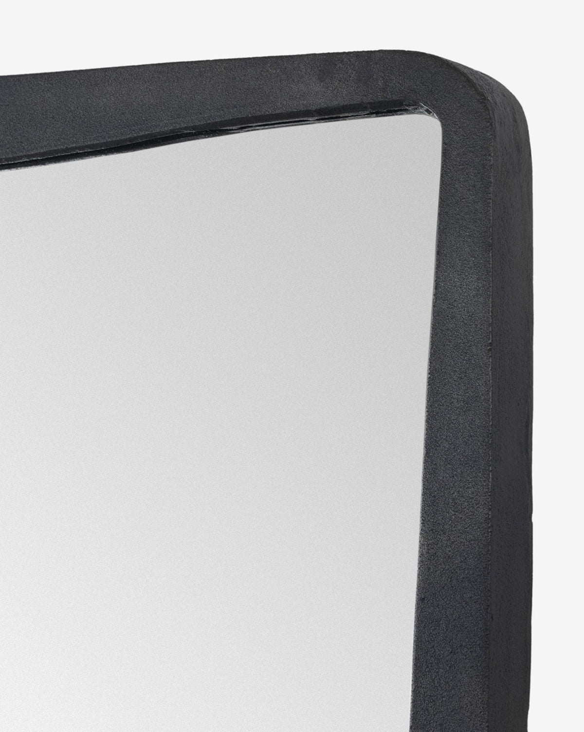 Close-up of the Penrod Floor Mirror’s corner, showcasing its thick, black, subtly textured cast aluminum frame against a plain white background—a striking sculptural accent for any home, by McGee & Co.