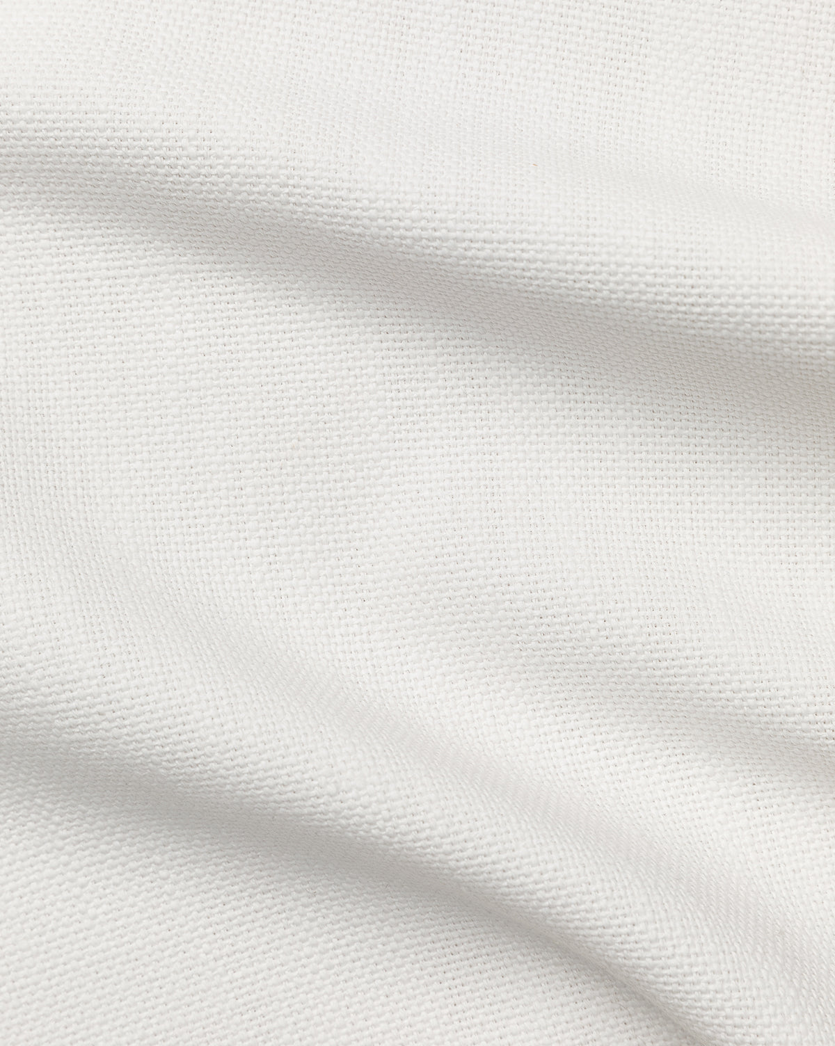 Close-up of Perennials Upholstery Swatch in white, showing a textured weave and soft folds. This solution-dyed acrylic fabric offers exceptional durability, making it ideal for performance upholstery applications.