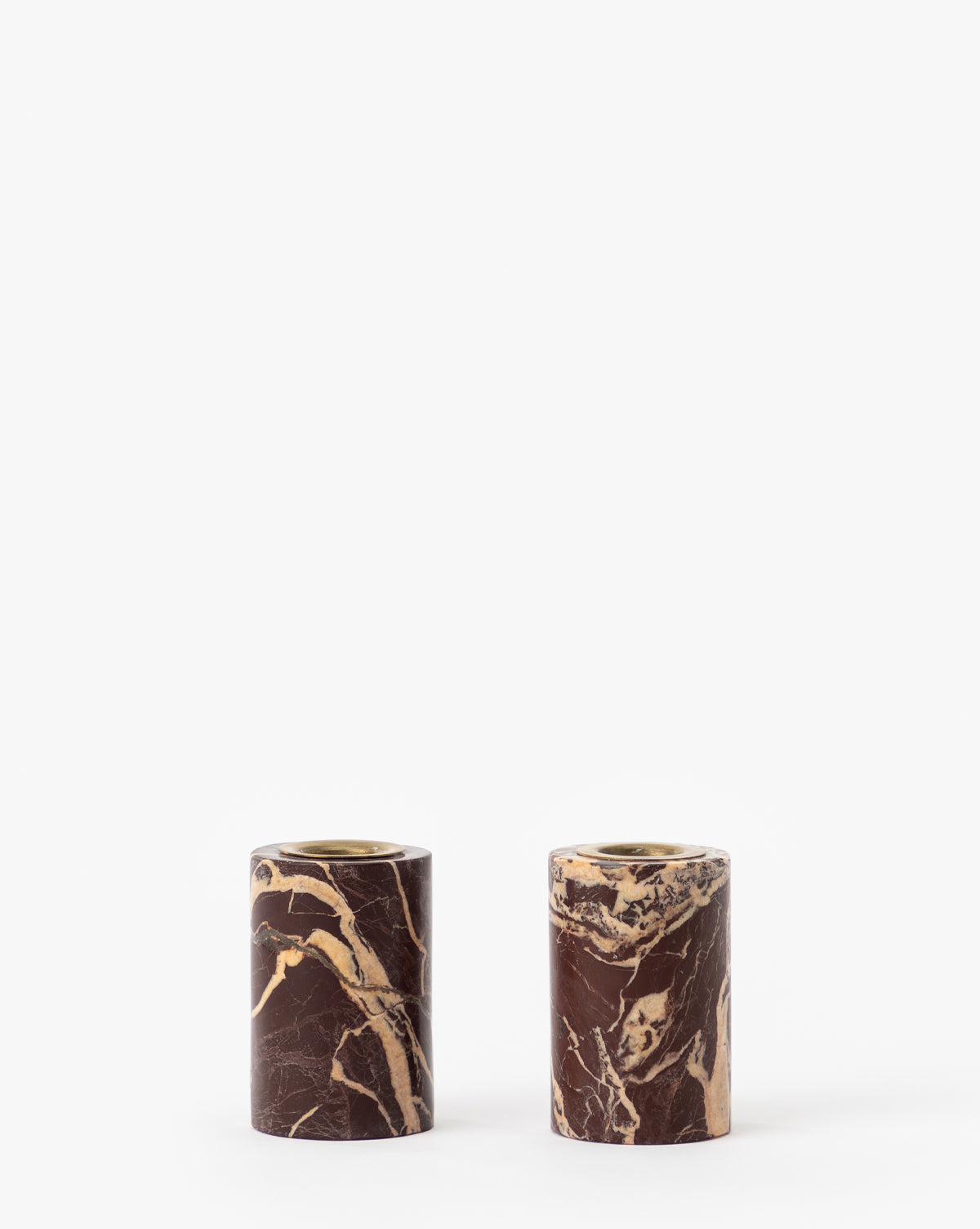 The Perrin Marble Taper Holders (Set of 2) feature brown and beige cylindrical marble holders with brass caps, displayed side by side against a plain white background.