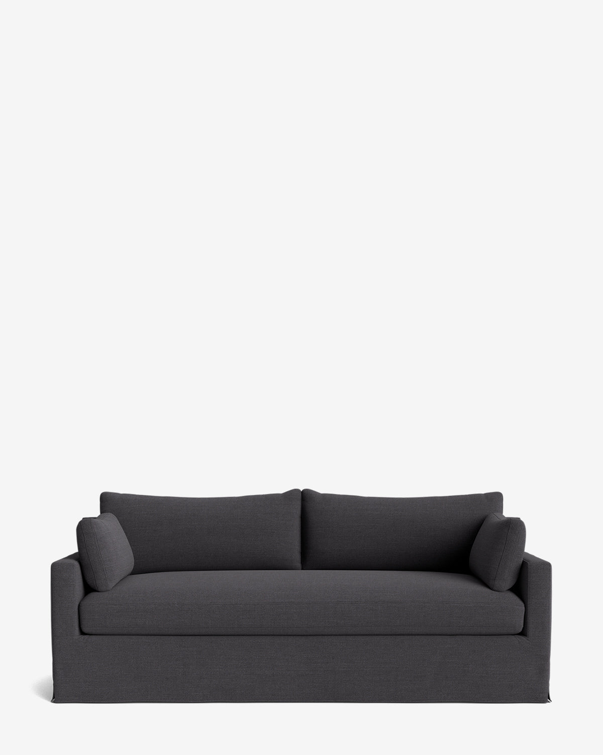 A modern dark gray Peterson Classic Slipcover Sofa (75-100) with straight arms, feather blend cushions, and two cylindrical side pillows, set against a plain white background by McGee & Co.