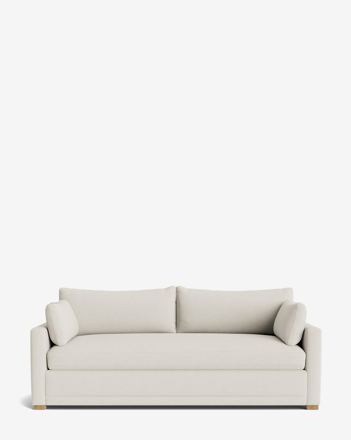 The Peterson Classic Upholstered Sofa (75 - 100) is a modern, light beige piece with two plush back cushions, two cylindrical side pillows, clean lines, and wooden legs, shown against a plain white background by McGee & Co.
