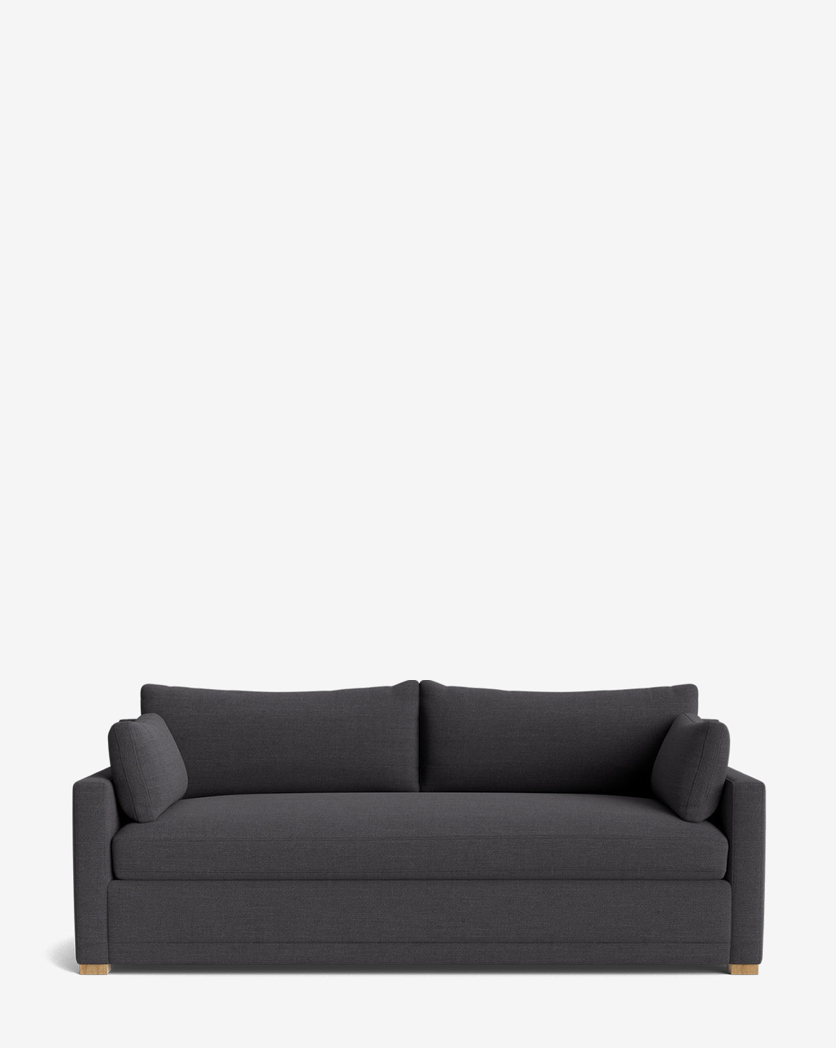 The Peterson Classic Upholstered Sofa (75 - 100) is a modern dark gray sofa with plush cushions, two seat and back pillows, and two cylindrical side pillows. Handcrafted with straight arms and wooden feet, shown against a plain white background by McGee & Co.