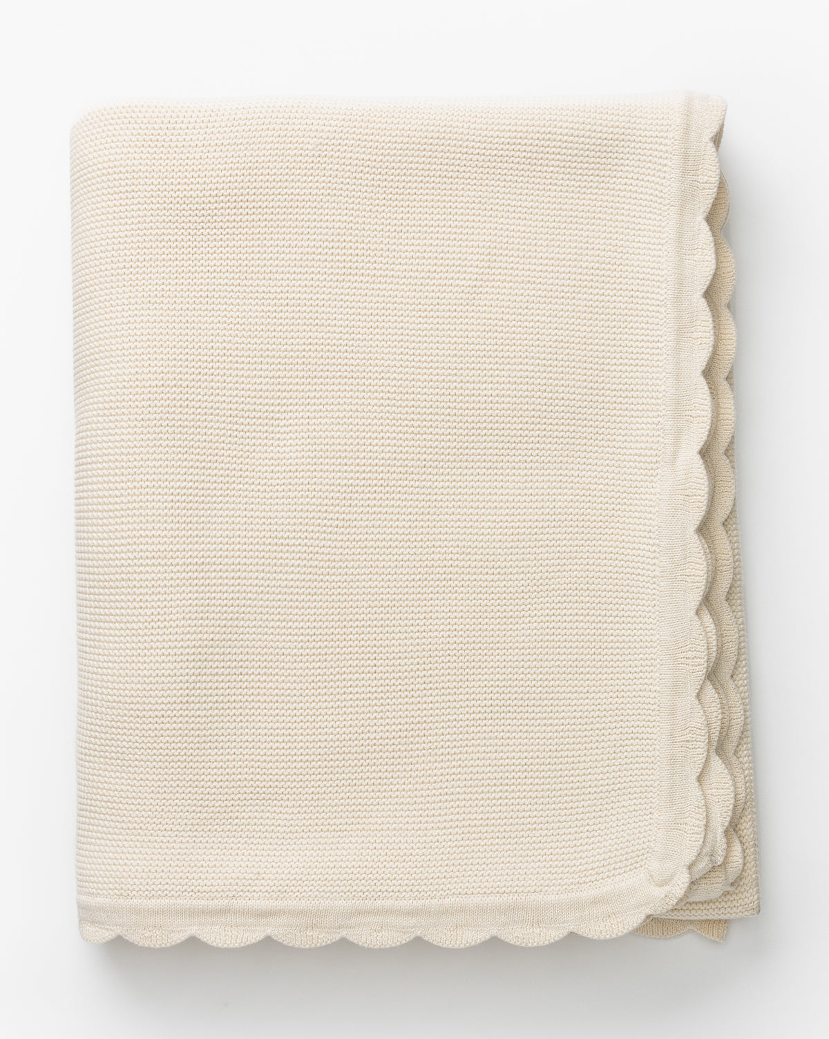 The Pinnacle Knit Kids Blanket, made from 100% cotton with scalloped edges and a folded cream finish, is shown on a white background.