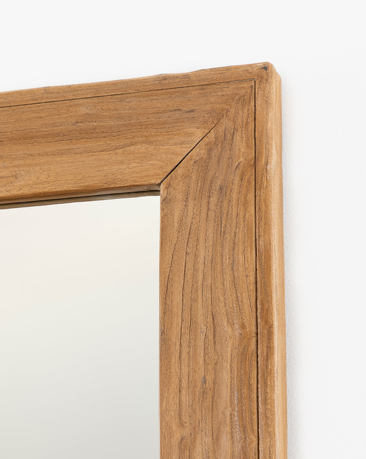 Close-up of the Pippen Floor Mirror’s top right corner, showcasing its honey elm-finished natural wood frame with visible wood grain and mitered joint, set against a white background by McGee & Co.