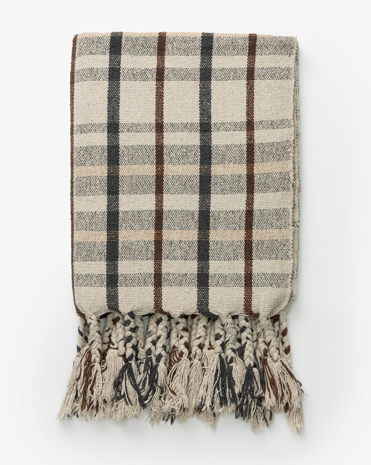 A Plaid Tasseled Throw in beige showcases a classic plaid design with brown and black accents and thick, braided tassels on one edge, elegantly displayed against a white backdrop.
