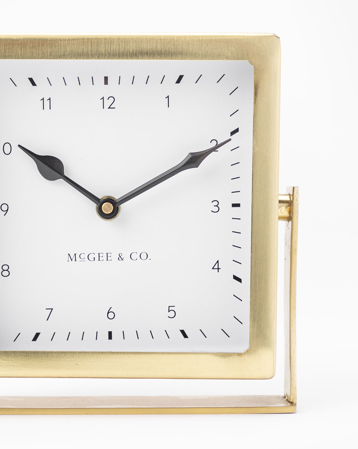 The Posey Table Clock features a square gold frame, white face, black tick marks, and black hands set to 10:10, with MCGEE & CO. at the center—an ideal nightstand clock or stylish desk accessory.