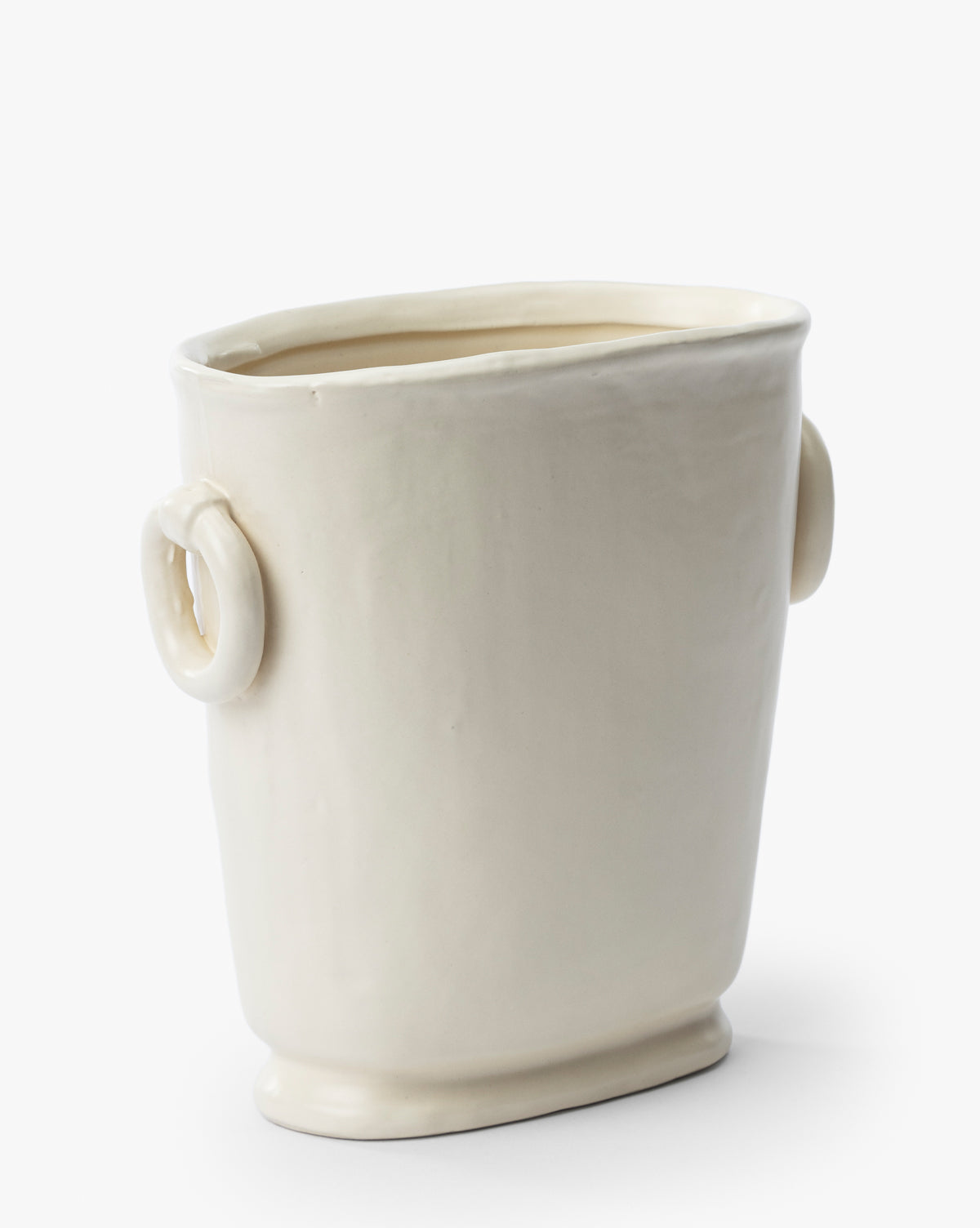The Powell Ceramic Vase, in a cream color with an uneven slanted rim, rounded base, and two circular side handles, is displayed against a plain white background.