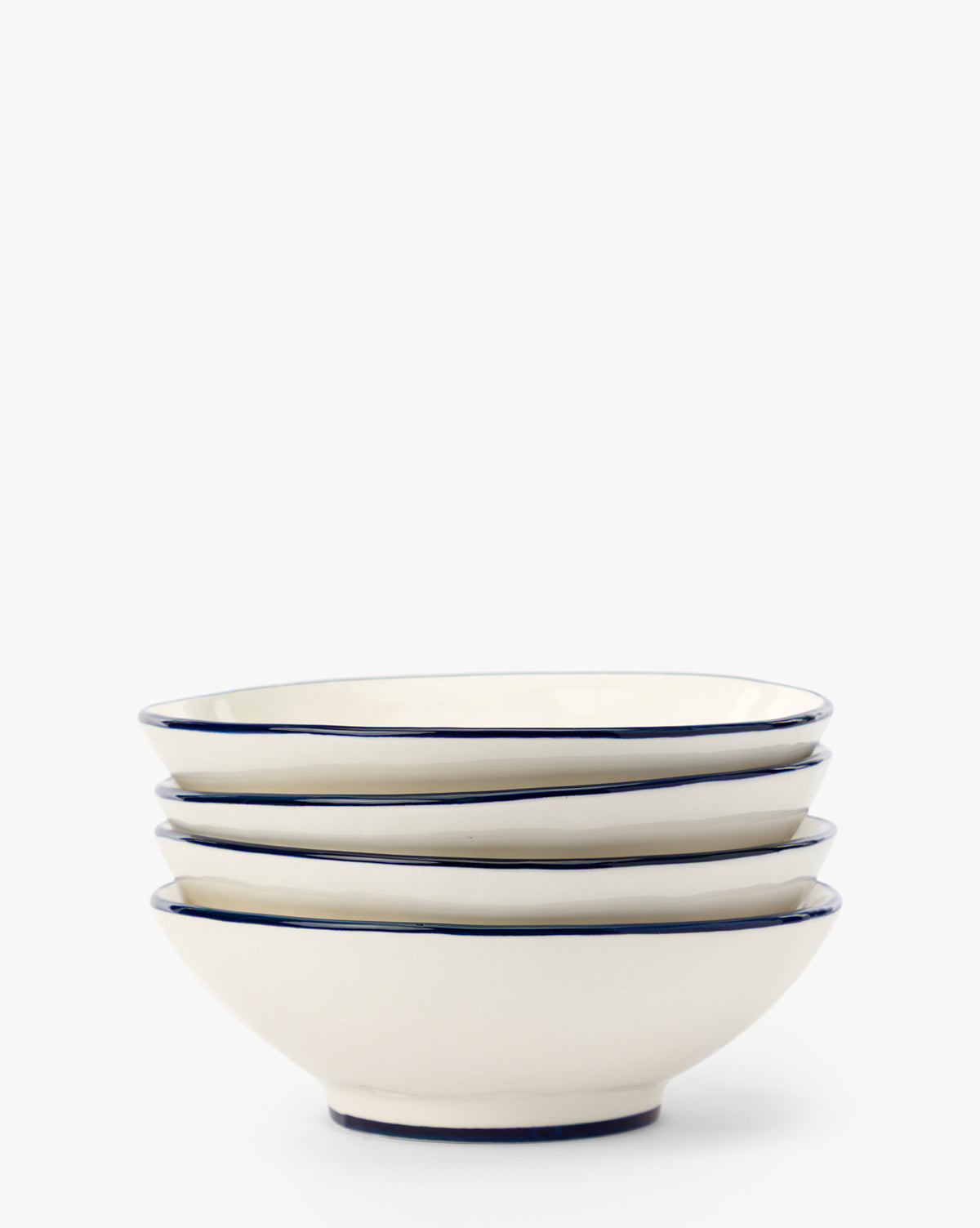 A set of four Pritchard Bowls, each with a creamy glaze and a delicate navy rim, arranged neatly against a plain white background by McGee & Co.