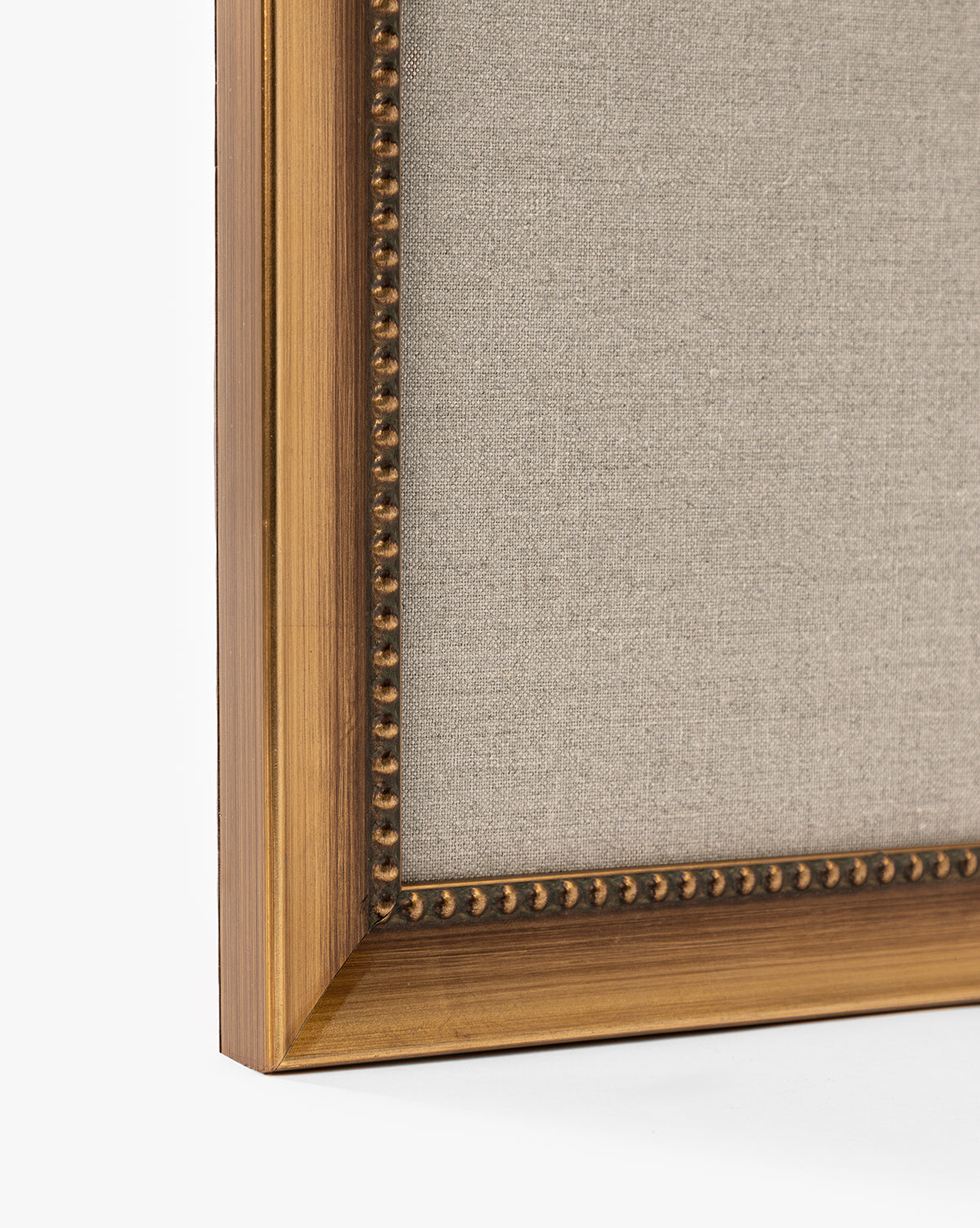 A close-up of the corner of a wooden frame with gold detailing and beaded inner edge displays Purple Irises in Vases. The warm brown finish, light beige fabric, and plain white background make it perfect for elegant home decor, by McGee & Co.