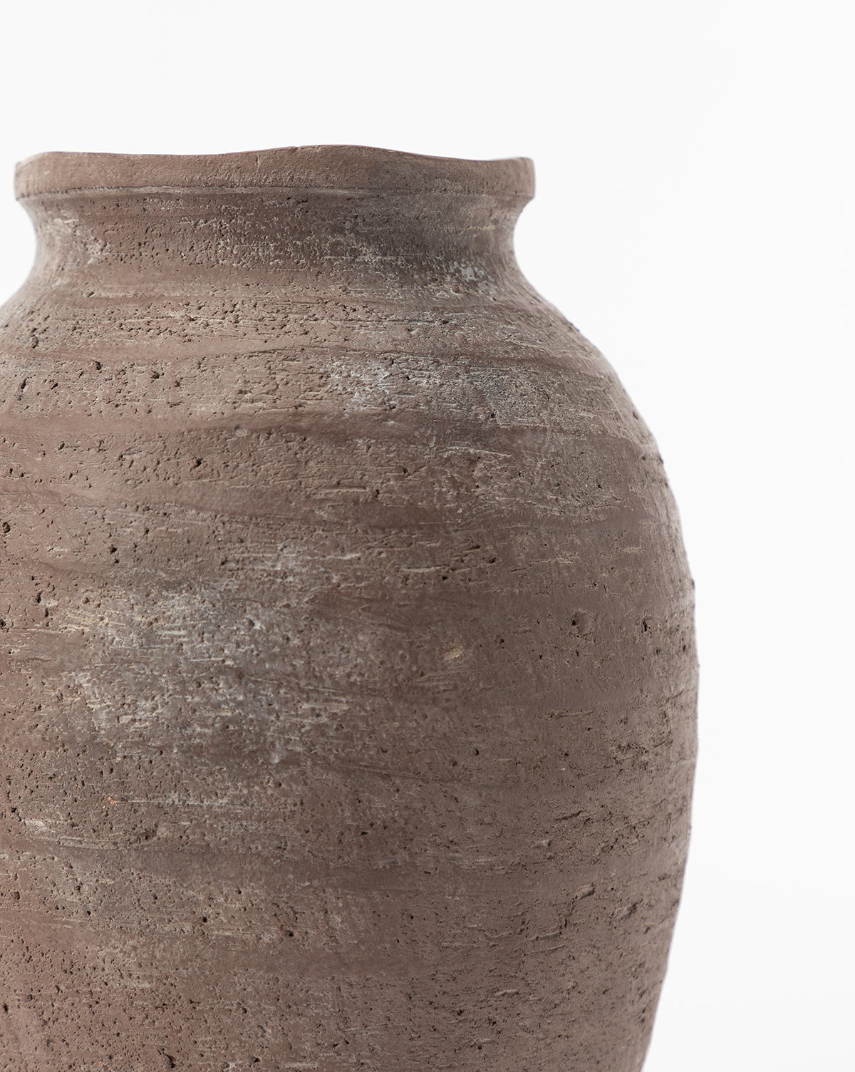A close-up of the Queta Terracotta Vase showcases its rustic, handmade design and rough, textured brown clay surface, with the upper portion and side visible against a plain white background.