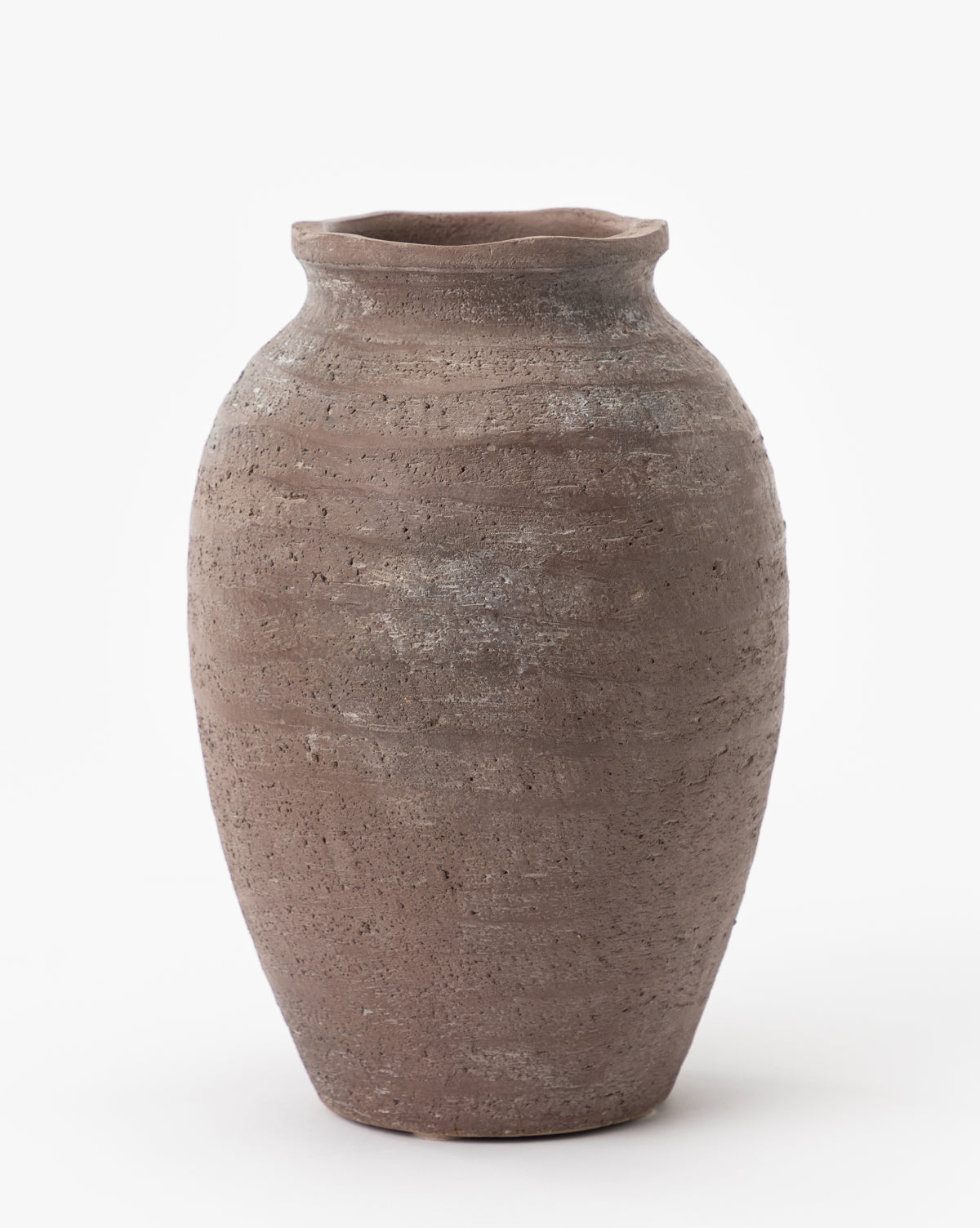 The Queta Terracotta Vase is a tall, rustic piece with a wide body, narrow neck, and flared rim. Handmade with a rough, textured surface in earthy brown tones, it stands out against a plain white background.