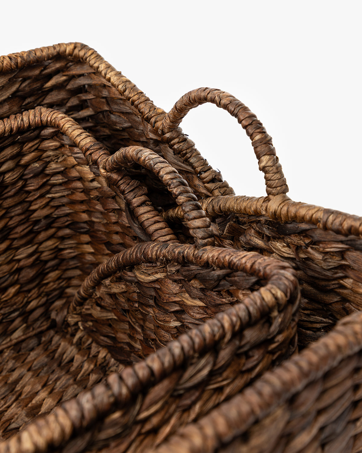 Close-up of two Quimby Baskets, handwoven from natural brown fibers with handles, shown nested together against a white background by McGee & Co.