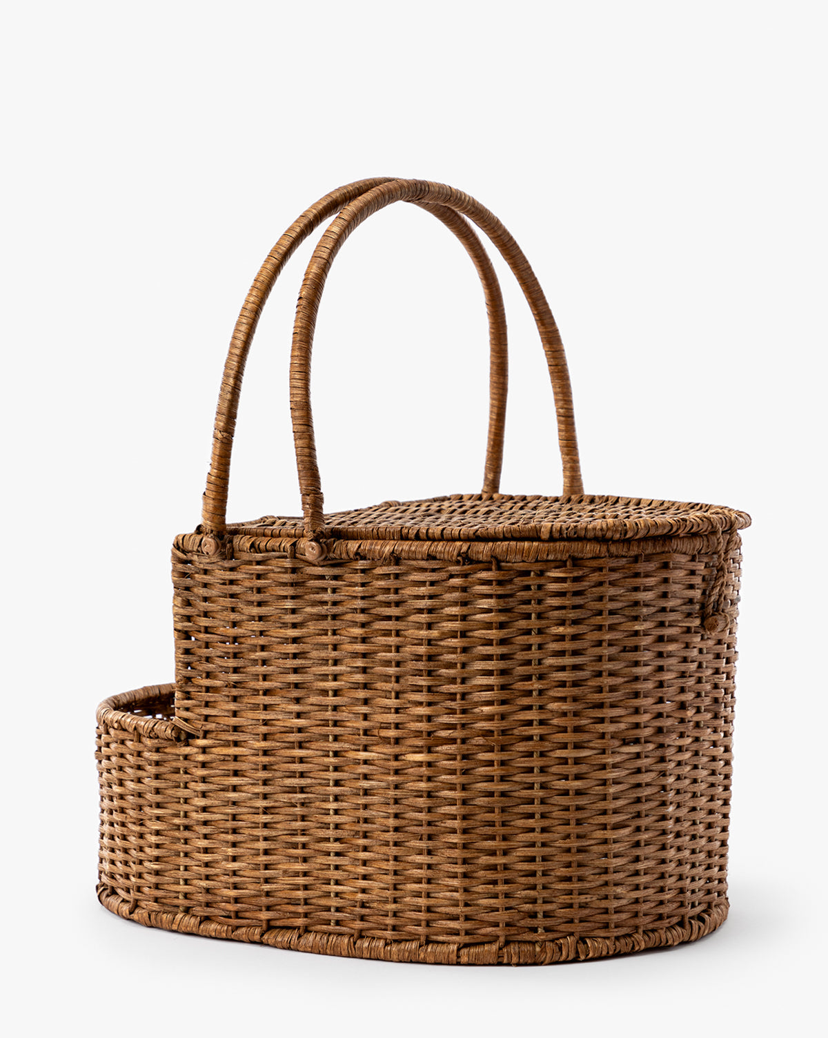 The Rattan Wicker Picnic Basket features a curved lid, two tall handles, and an attached side compartment, shown against a plain white background, by McGee & Co.