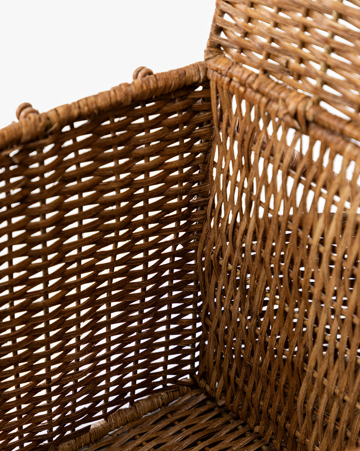 Close-up view of the Rattan Wicker Picnic Baskets corner shows its intricate brown woven pattern—a stylish storage solution—against a white background, by McGee & Co.