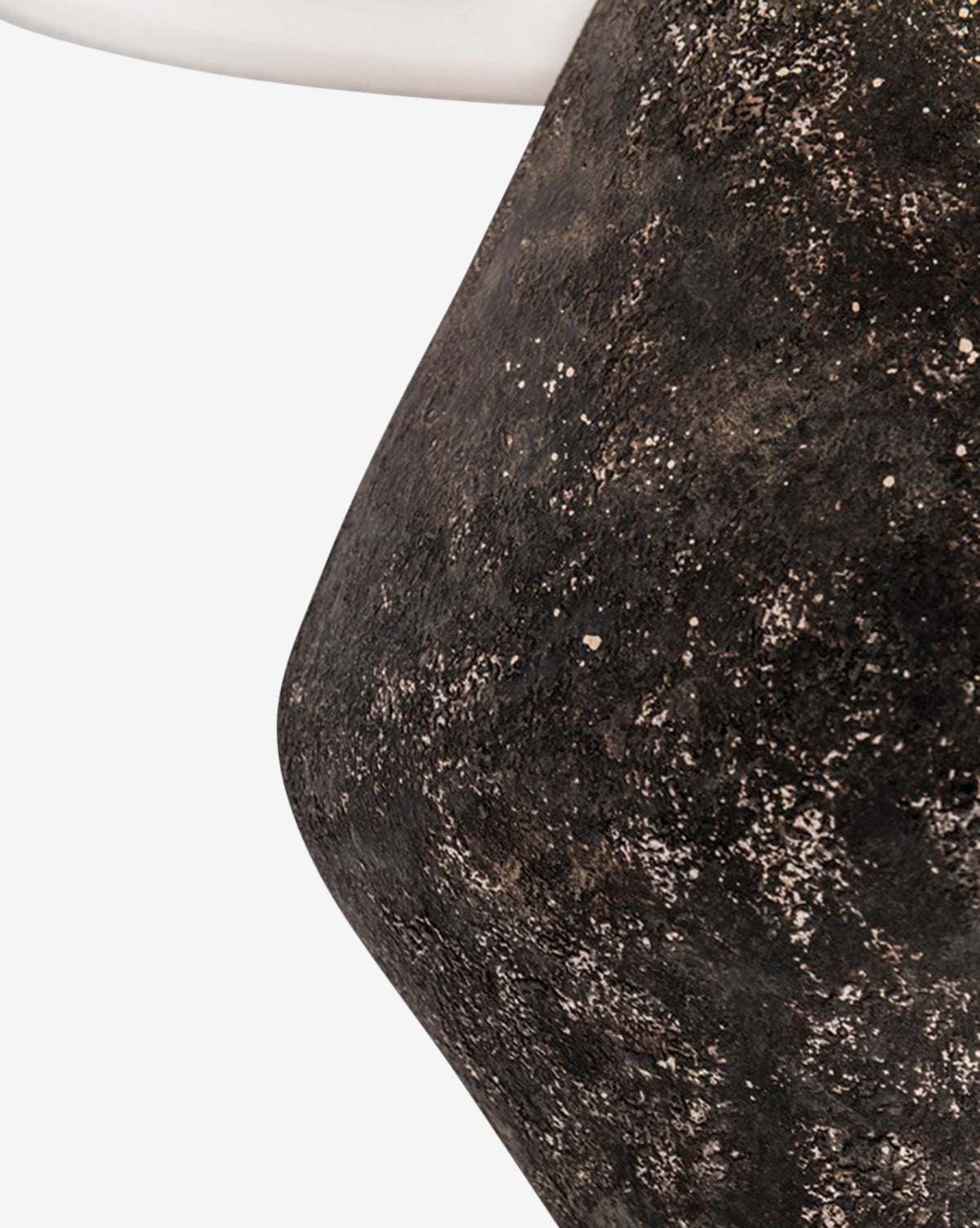 Close-up of the Rayan Table Lamps dark, speckled graystone base with a rounded shape and part of its smooth white fabric drum shade visible in the top left corner, set against a plain white background, by McGee & Co.